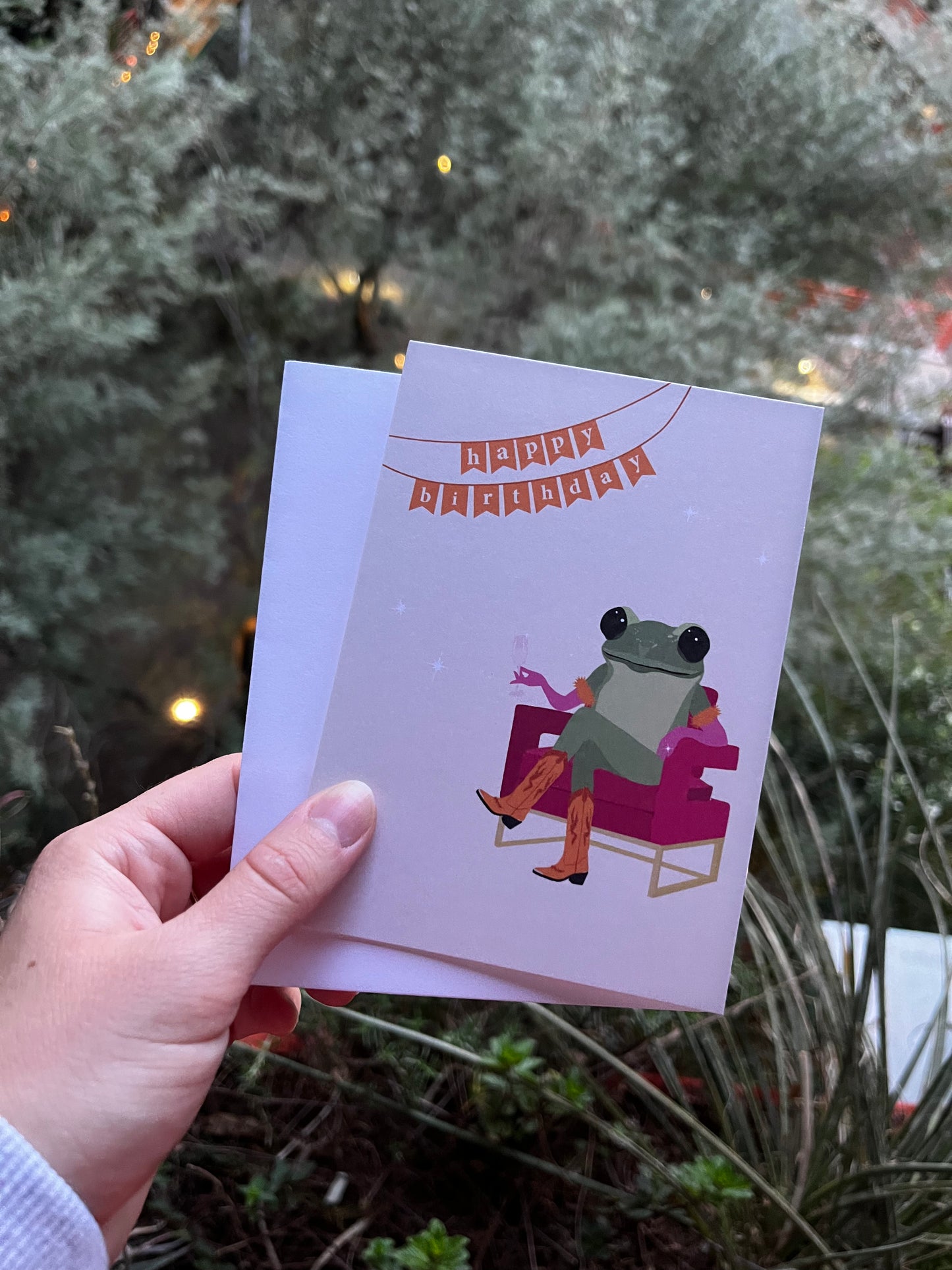card with illustration of a frog in cowgirl boots sitting in a hot pink chair holding champagne with a happy birthday banner